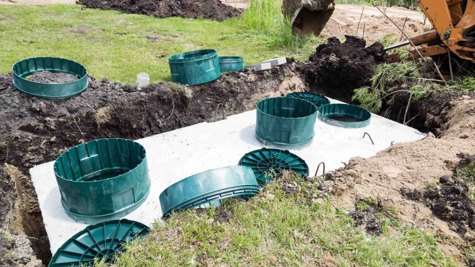 New septic system installation with green tank risers set on a concrete tank in an open excavation
