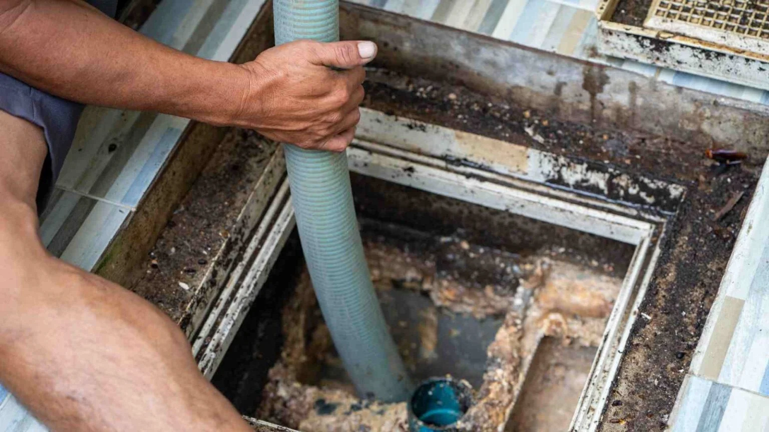 Technician lowering a hose into an open tank while making a septic repair